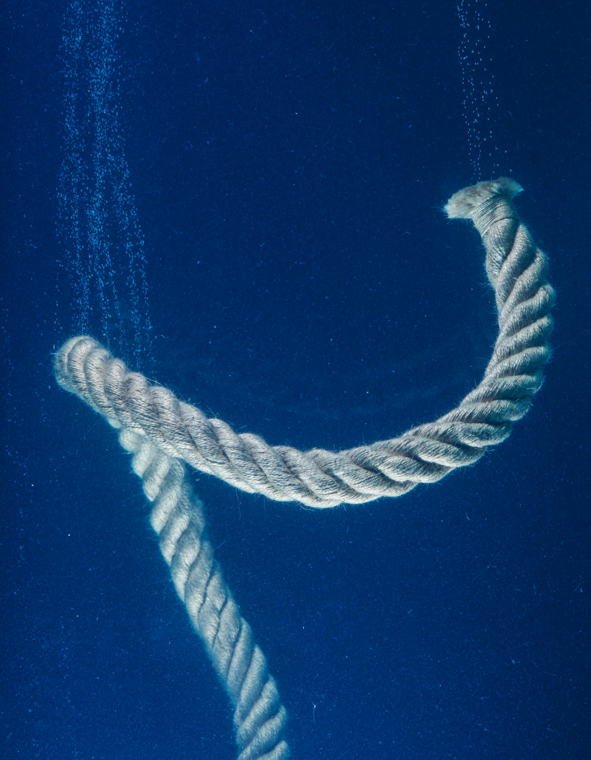 Close-up of a twisting rope submerged in the serene deep blue waters. Captivating underwater scene. Paradise Part 3 — The Essential Architecture of Continuity