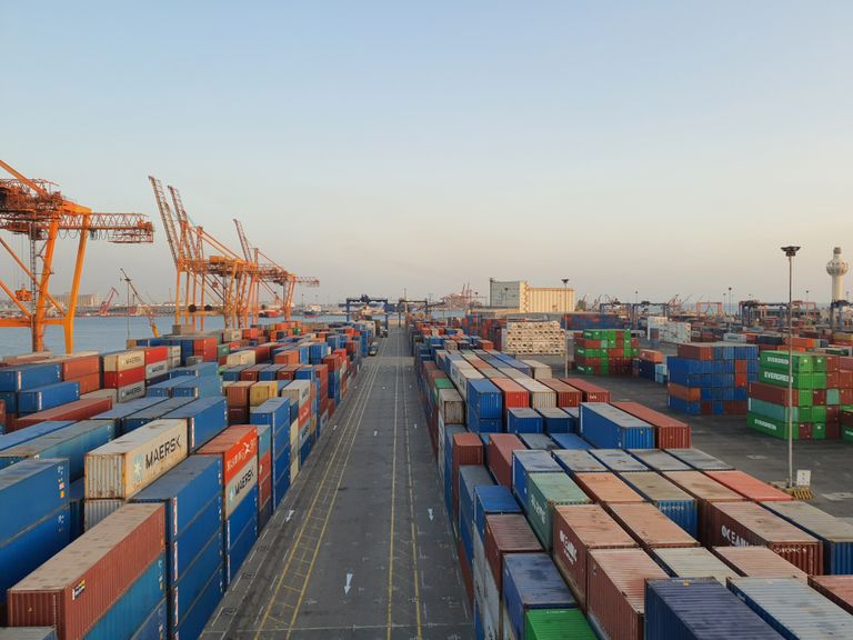 A bustling port scene with colorful cargo containers at sunrise. Ideal for logistics concepts. Infographic on supply chain stability showing pillars of sourcing, logistics, buffers, and governance.”
