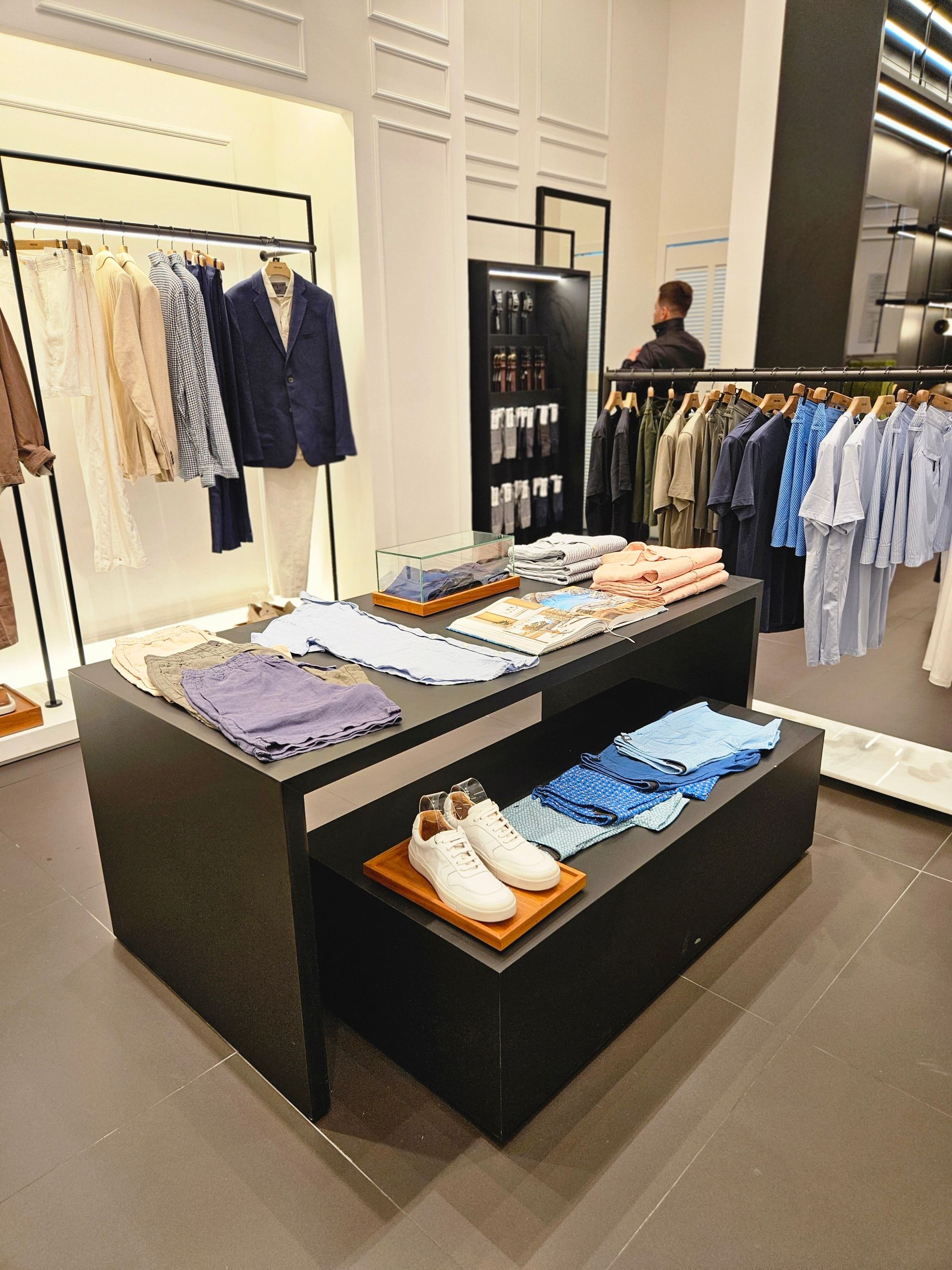 Contemporary clothing store showcasing tailored suits, casual shirts, and accessories. Modern Indian retail store interior with neatly arranged clothing racks, representing Trent’s evolution from Lakmé to Westside and Zudio.